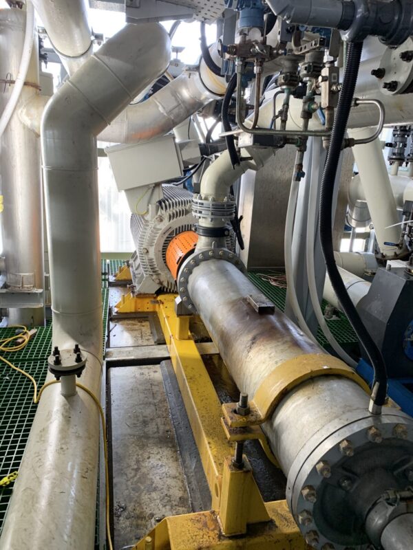 Industrial pump and large pipeline with yellow supports.