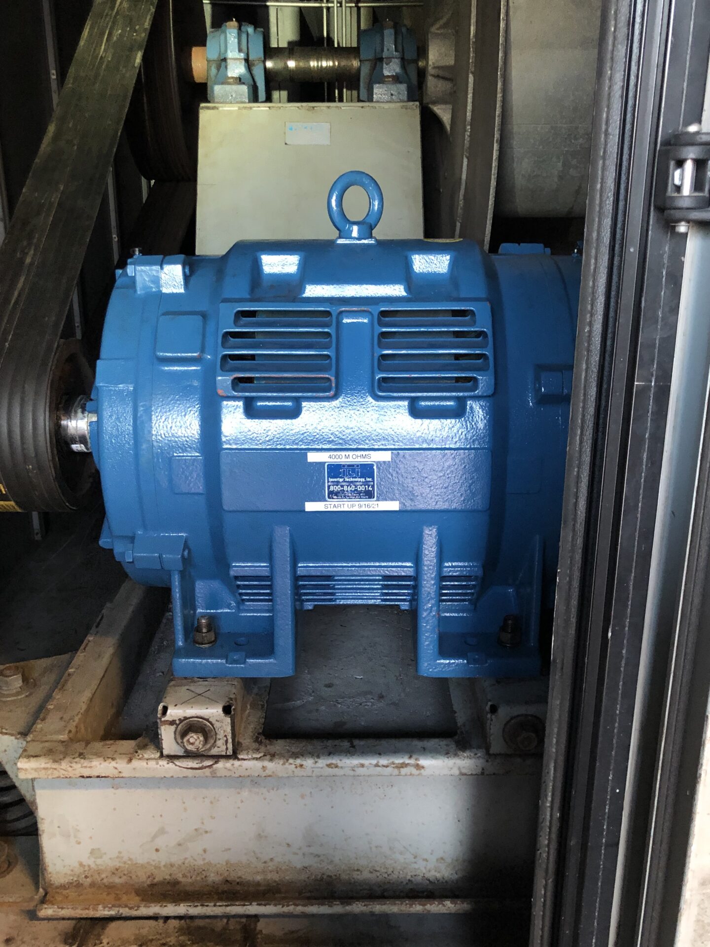 Blue industrial electric motor mounted on metal base.